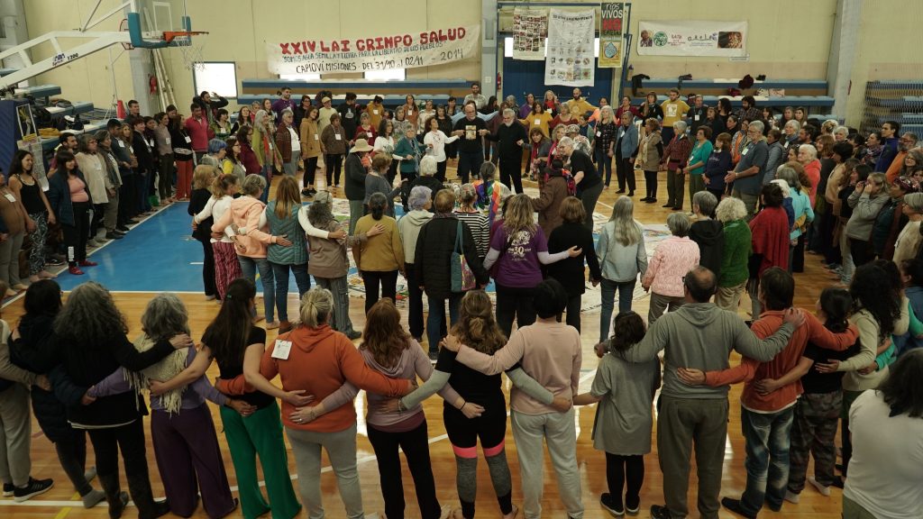 Reunión de muchas personas en ronda dentro de un polideportivo